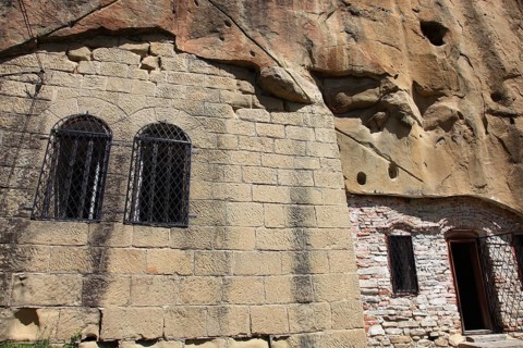 Corbii de Piatra rock monastery, stone ravens carved into a massive, 30-meter high sandstone wall,