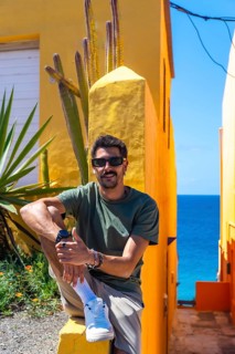 Young man enjoying the vibrant colors and ocean view in puerto de mogan, a picturesque village in