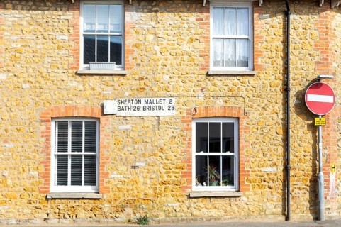 Vintage listed road distance mileplate sign historic old stone building, Fore Street, Castle Cary,