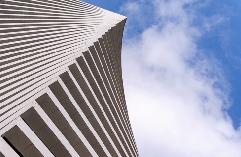 Angular view of a modern building's facade with sleek lines against a bright sky. The unique