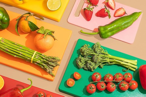 A vibrant display of fresh fruits and vegetables on multicolored cutting boards, featuring oranges,