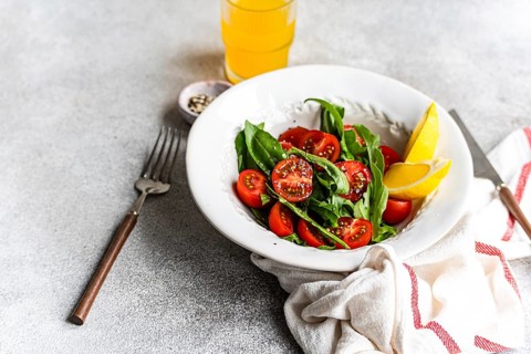 Fresh arugula and herb salad topped with cherry tomatoes, Himalayan salt, olive oil, and seeds.