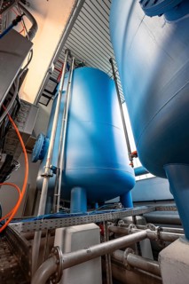 Large, blue tanks in a room full of technical equipment and pipes, ENCW Netze Calw waterworks,