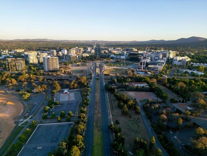 From above drone shot of Canberra, Australia's capital, bathed in soft evening light. The drone