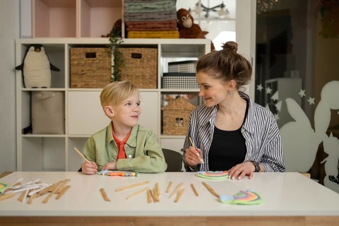 A joyful and creative classroom moment where a child and teacher engage in an imaginative art