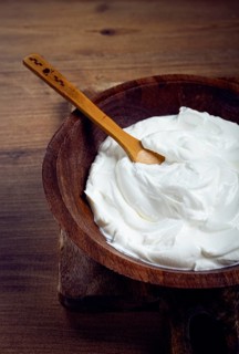 Sour cream in a wooden bowl, on a wooden table, top view, close-up, no people