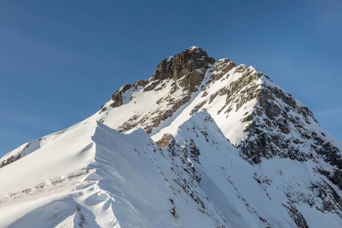 A breathtaking view of a snow-covered mountain peak, ideal for ski touring, showcasing the pristine