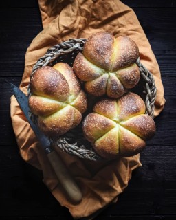 A warm, freshly baked pumpkin bread sits invitingly in a woven basket atop an orange cloth. The