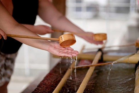 Close-up of people performing the traditional hand washing ritual at Shitenno-ji temple in Osaka,