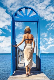 A young brunette passing a blue door in the Caribbean Sea on Roatan Island. Honduras