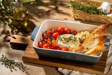 A freshly baked Camembert cheese with cherry tomatoes and crispy toasted bread, garnished with