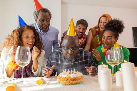 A joyful group at a festive birthday celebration. The guest of honor wears a party hat, ready to