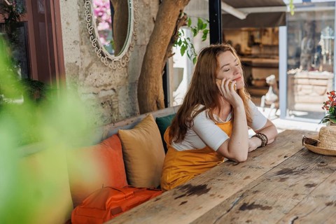 A mature woman, wearing an orange and yellow outfit, enjoys a phone call during her vacation in an