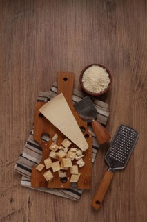 Freshly sliced and grated cheese, parmesan cheese, Gran gusto. Grana padano. on a wooden chopping