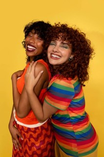 Two joyful women embrace warmly, expressing happiness and friendship. They wear bright, colorful