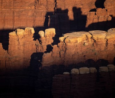 Shadowed, towering rock formations cast intricate patterns under dramatic lighting at Canyonlands