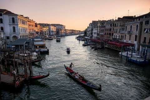 View of the Grand Canal with gondoliers at sunset, picturesque evening mood with palazzos on the