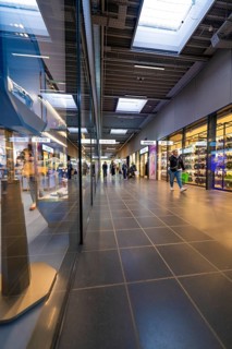 Interior view of a modern shopping centre with shops and people walking past, Outlet City