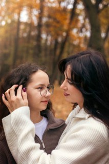 A tender moment between a mother and daughter, surrounded by warm autumn colors in a forest setting
