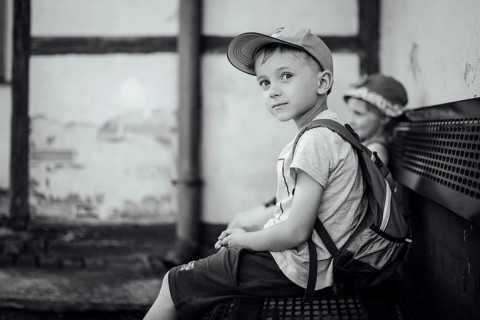 Boy and girl waiting on the bench for a train during warm summer day