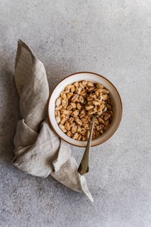 Top view of a ceramic bowl filled with puffed wheat cereals, accompanied by a silver spoon and a