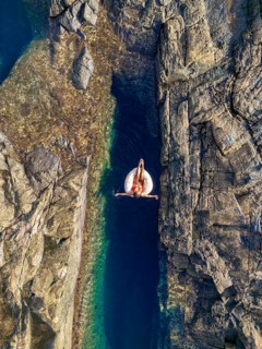 Top view of an unrecognizable woman relaxing on an inflatable float in a serene, narrow natural