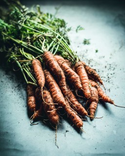 A bunch of freshly harvested carrots with vibrant green tops, showcasing their earthy texture