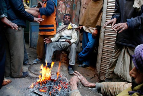 New Delhi, India, 15.01.10 - Traders and workers warm up by a fire at the market in New Delhi,