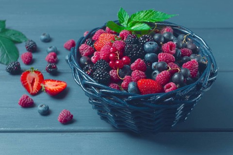 Mix of fresh berries, in a basket, on a wooden gray table, no people, top view
