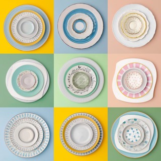 A collection of ceramic plates arranged in a grid, showcasing various designs and colors on vibrant