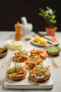 Freshly prepared open-faced sandwiches with smoked salmon, pickles, and watercress sprouts on