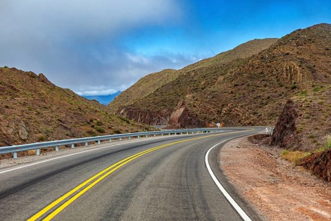 Curvy road through a dry, mountainous landscape, blue sky, roads through the Quebrada de Cafayate