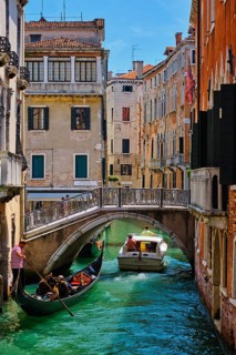 VENICE, ITALY, JULY 19, 2018: Narrow canal between colorful old houses with gondola boat with