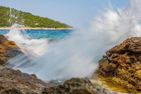 Wellen brechen an einem Felsen im Meer an einem sonnigen Tag auf der Insel Cres, Kroatien