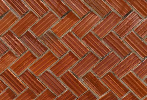 Face brick wall with a classic herringbone pattern. The red-toned bricks are arranged diagonally,