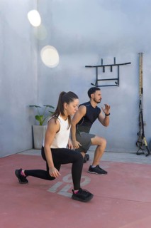 Two fitness professionals demonstrating proper lunge form in an outdoor training area, highlighting