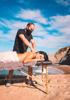 Massages on the coast near the sea, masseuse with face mask in the coronavirus pandemic