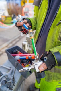 Worker holding a hose connector with gloves on a construction site, Wend Glasfasermontage during
