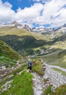 Mountaineer on hiking trail in front of picturesque mountain landscape, rocky mountain peaks with