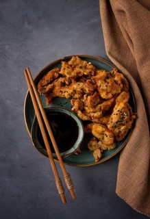 Fried meat in batter, deep-fried, with sesame seeds, and soy sauce, on a gray table, there are no