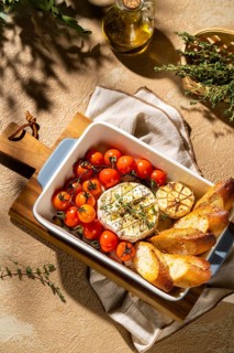 Savor the sight of baked Camembert with cherry tomatoes, garlic, and fresh herbs. The dish is