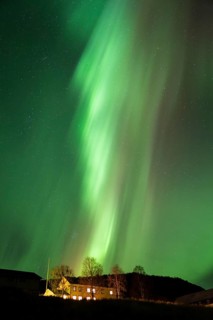 Intense northern lights (aurora borealis) over an illuminated house, Alvdal, Hedmark, Innlandet,