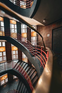 Interior view of a multi-storey spiral staircase with red railings in industrial style,