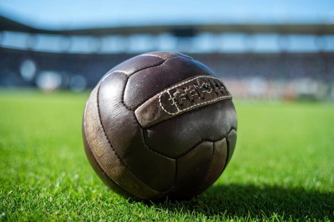 Old soccer ball on the grass at the stadium