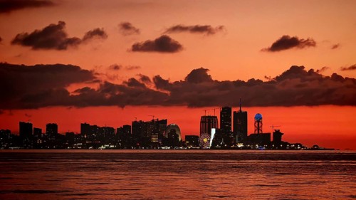 City view at sunset with illuminated buildings and a waterway in the foreground, Batumi, Georgia