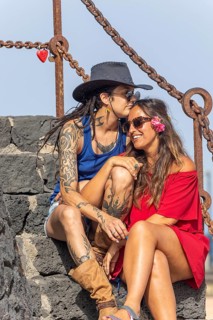 A joyful lesbian couple shares a tender moment on stone steps during summer. Embracing under a