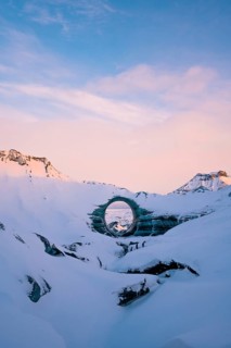 A naturally formed circular ice arch stands prominently amid the snow-covered landscape of Katla
