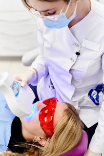 A dental professional uses advanced blue light technology to perform a teeth whitening procedure on
