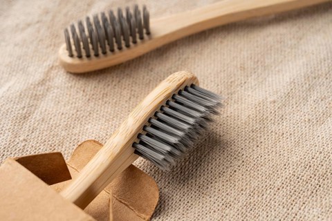 From above view of bamboo toothbrushes with soft bristles on a textured beige fabric. Packaged