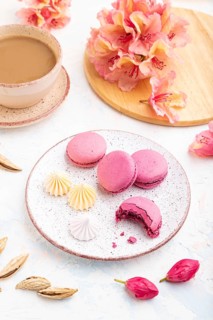 Purple macarons or macaroons cakes with cup of coffee on a white concrete background decorated with